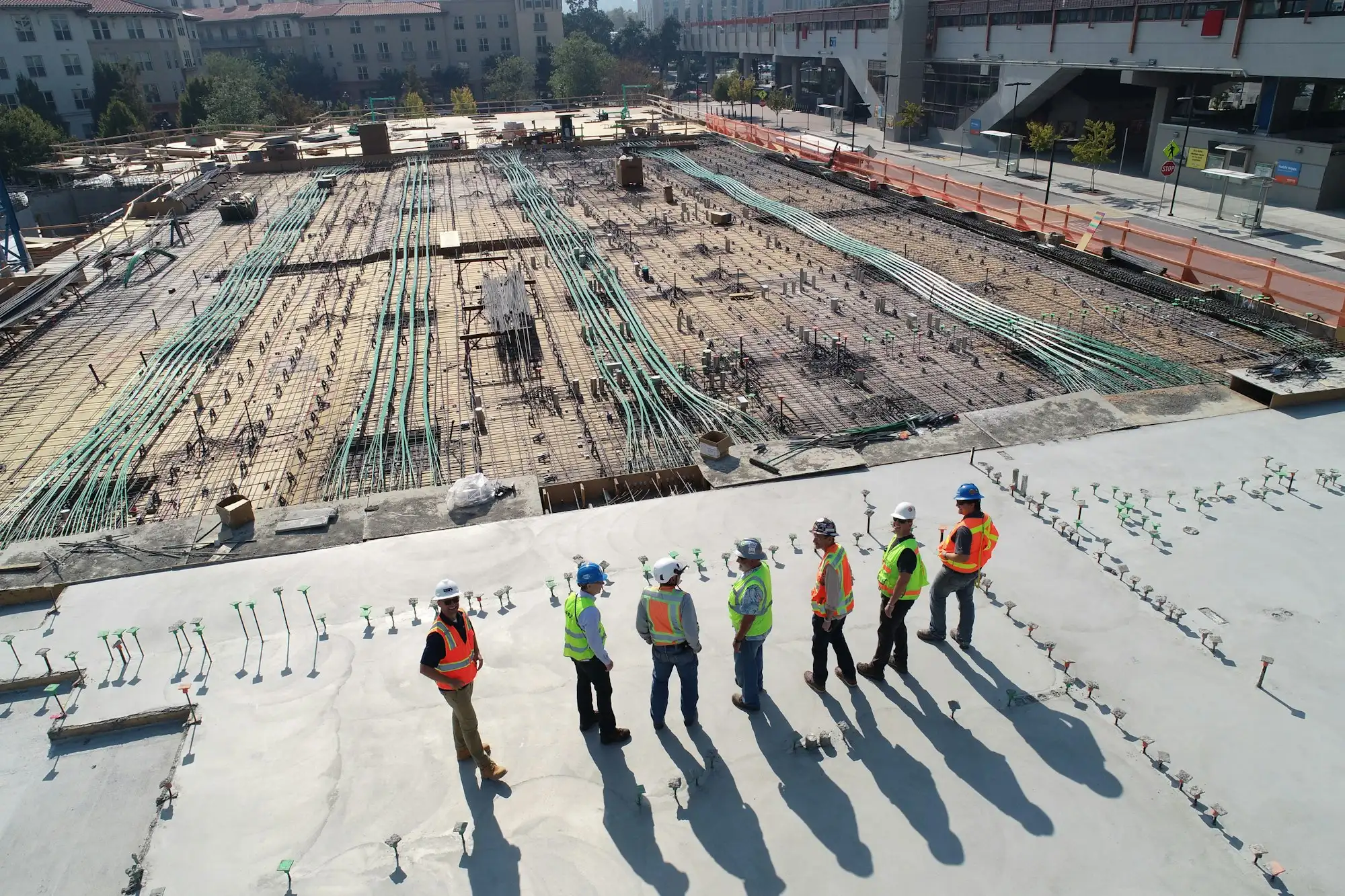 Équipe de chantier en gilets de sécurité sur une dalle béton, à côté d’un plancher en cours de ferraillage.